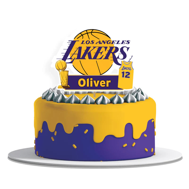 LA Lakers cake toppers with basketball graphics and custom text on frosted cake, flat lay style