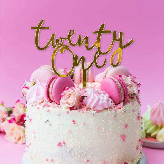 Gold acrylic cake topper in the shape of 'Twenty One' for a 21st birthday celebration